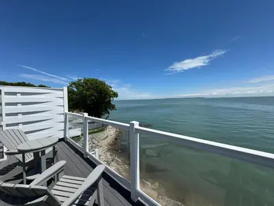 a balcony with a table and chairs and the ocean at Put-in-Bay Waterfront Condo #209 in Put-in-Bay