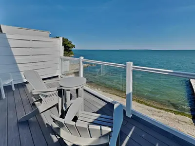 a balcony with two chairs and a table and the ocean at Put-in-Bay Waterfront Condo #206 in Put-in-Bay