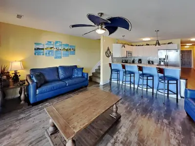 a living room with a blue couch and a kitchen at Put-in-Bay Waterfront Condo #206 in Put-in-Bay