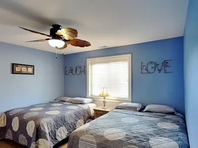 two beds in a room with blue walls and a ceiling fan at Put-in-Bay Waterfront Condo #206 in Put-in-Bay