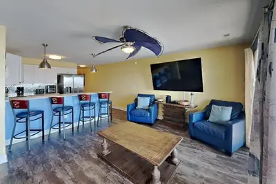 a living room with a bar and blue chairs at Put-in-Bay Waterfront Condo #208 in Put-in-Bay