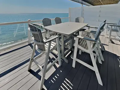 a table and chairs on a deck with the ocean at Put-in-Bay Waterfront Condo #208 in Put-in-Bay