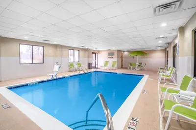 a pool in a hotel room with chairs and tables at Holiday Inn Express Hotel & Suites Ashland by IHG in Ashland
