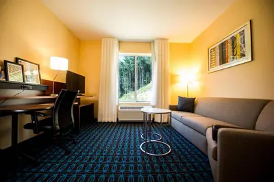 a hotel room with a couch and a desk and a window at Fairfield by Marriott Cambridge in Cambridge