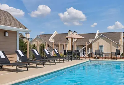 a pool with chaise lounge chairs and a table with an umbrella at Sonesta Simply Suites Cleveland Airport in Middleburg Heights