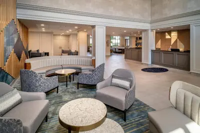 a lobby with couches chairs and tables and a kitchen at Delta Hotels by Marriott Huntington Downtown in Huntington
