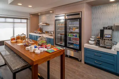 a kitchen with a table and a refrigerator at Delta Hotels by Marriott Huntington Downtown in Huntington