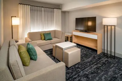 a living room with a couch and a flat screen tv at Delta Hotels by Marriott Huntington Downtown in Huntington