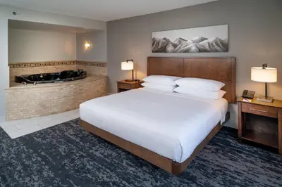 a hotel room with a large bed and a tub at Delta Hotels by Marriott Huntington Mall in Barboursville