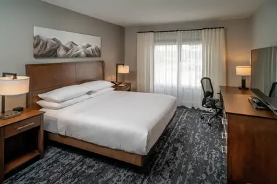 a bedroom with a bed and a desk and a television at Delta Hotels by Marriott Huntington Mall in Barboursville