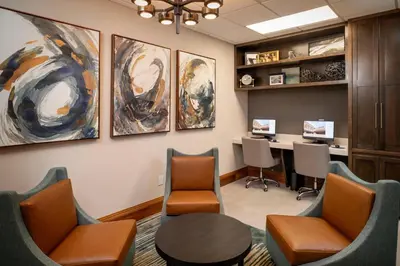 a waiting room with chairs and a table and a desk at Delta Hotels by Marriott Huntington Mall in Barboursville