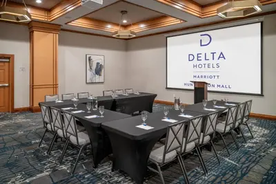 a conference room with tables and chairs and a screen at Delta Hotels by Marriott Huntington Mall in Barboursville
