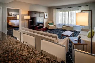 a hotel room with a king bed and a living room at Delta Hotels by Marriott Huntington Mall in Barboursville