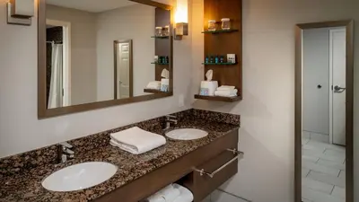 a bathroom with two sinks and a mirror at Delta Hotels by Marriott Huntington Mall in Barboursville