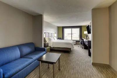 a living room with a blue couch and a bed at Holiday Inn Express Hotel & Suites Bryan-Montpelier by IHG in Holiday City
