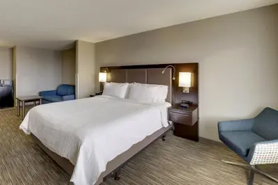 a hotel room with a large bed and a blue chair at Holiday Inn Express Hotel & Suites Bryan-Montpelier by IHG in Holiday City