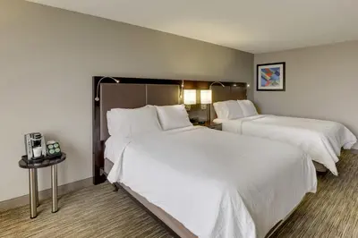 two beds in a hotel room with white sheets at Holiday Inn Express Hotel & Suites Bryan-Montpelier by IHG in Holiday City