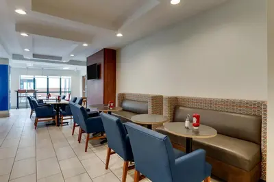 a restaurant with tables and chairs and a couch at Holiday Inn Express Hotel & Suites Bryan-Montpelier by IHG in Holiday City