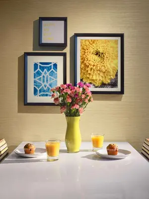 a table with a yellow vase with flowers and cups at Sonesta Simply Suites Cleveland Westlake in Westlake