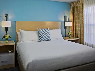 a bedroom with a large bed with blue walls and two lamps at Sonesta Simply Suites Cleveland Westlake in Westlake