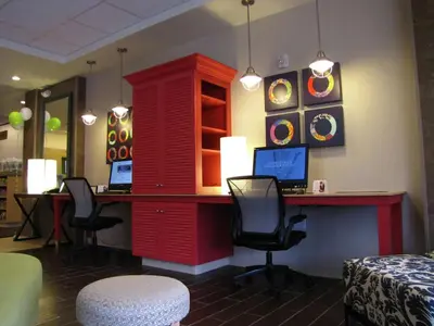 a red desk with two chairs and a desk with a computer at Home2 Suites By Hilton-Cleveland Beachwood in Beachwood