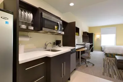 a kitchen with a sink and a room with a bed at Home2 Suites by Hilton Cincinnati Liberty Township in Wetherington
