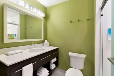 a green bathroom with a sink and a mirror at Home2 Suites by Hilton Cincinnati Liberty Township in Wetherington