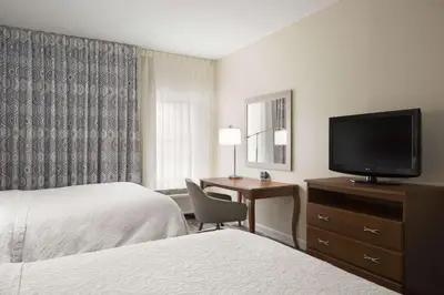a hotel room with a bed and a desk with a television at Hampton Inn Findlay in Findlay