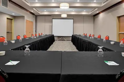 a conference room with tables and chairs and a white screen at Holiday Inn Hotel & Suites Lima by IHG in Lima