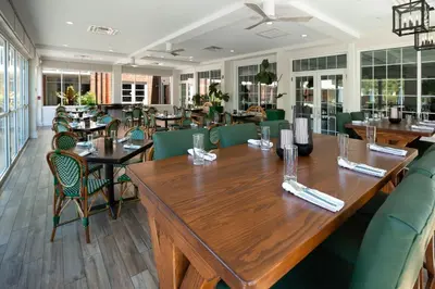 a restaurant with wooden tables and green chairs at Ohio University Inn and Conference Center in Athens