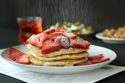 a plate of pancakes with strawberries on a table at Ohio University Inn and Conference Center in Athens