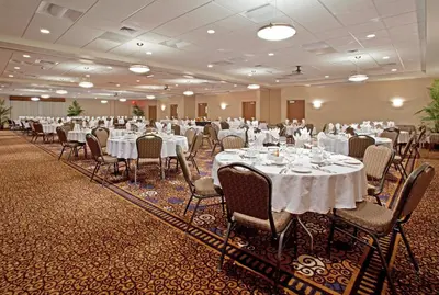 a banquet hall with white tables and chairs at Holiday Inn Purdue - Fort Wayne by IHG in Fort Wayne