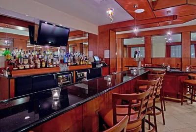 a bar with a lot of bottles of alcohol at Holiday Inn Purdue - Fort Wayne by IHG in Fort Wayne