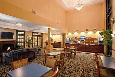 a hotel lobby with tables and chairs and a fireplace at Holiday Inn Express Hotel & Suites Cleveland-Richfield by IHG in Brecksville