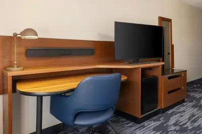 a room with a desk with a tv and a blue chair at Fairfield Inn and Suites by Marriott Cincinnati Eastgate in Eastgate