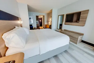 a bedroom with a white bed and a flat screen tv at Holiday Inn Express Hotel & Suites Ohio State University- OSU Medical Center by IHG in Columbus