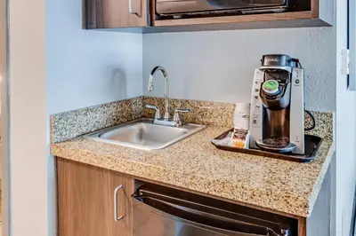 a kitchen with a sink and a coffee maker on a counter at Holiday Inn Express Hotel & Suites Ohio State University- OSU Medical Center by IHG in Columbus