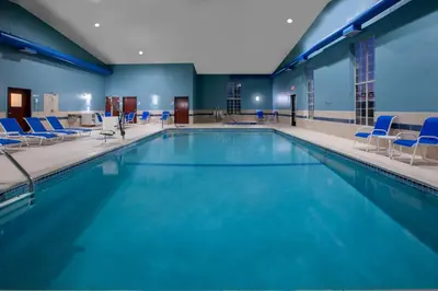 a large swimming pool with blue chairs in a building at Holiday Inn Express Hotel & Suites Woodhaven by IHG in Woodhaven