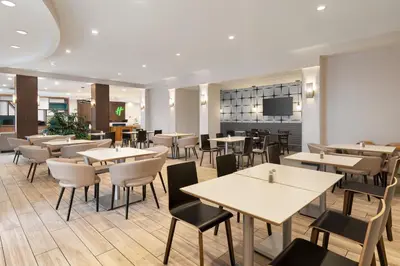 a restaurant with tables and chairs and a television at Holiday Inn Florence by IHG in Florence