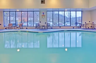 a pool in a hotel room with chairs and tables at Holiday Inn Express Winfield - Teays Valley by IHG in Hurricane