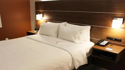 a hotel room with a bed with a phone on it at Holiday Inn Express Winfield - Teays Valley by IHG in Hurricane