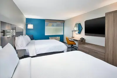 a hotel room with two beds and a flat screen tv at Holiday Inn Express Hotel & Suites Wauseon by IHG in Wauseon