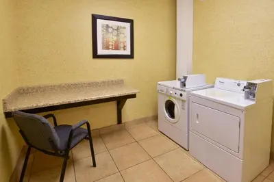 a laundry room with a washing machine and a chair at Holiday Inn Express Hotel & Suites Wauseon by IHG in Wauseon