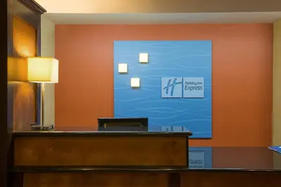 a reception desk in a hotel room with a sign on the wall at Holiday Inn Express Hotel & Suites Wauseon by IHG in Wauseon