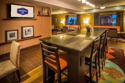 a bar in a hotel room with chairs and a living room at Hampton Inn Monroe in Monroe