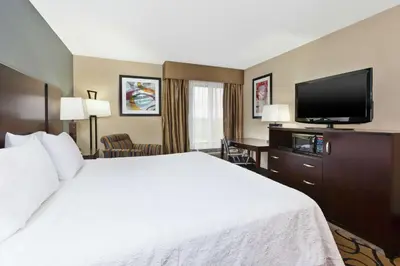 a hotel room with a bed and a flat screen tv at Hampton Inn Monroe in Monroe