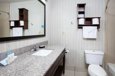 a bathroom with a sink and a toilet and a mirror at Hampton Inn Monroe in Monroe