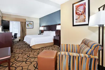 a hotel room with a bed and a chair at Hampton Inn Monroe in Monroe