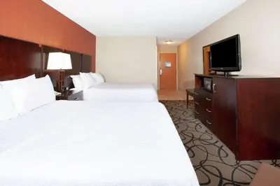 a hotel room with two beds and a flat screen tv at Hampton Inn Monroe in Monroe