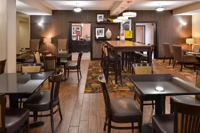 a restaurant with tables and chairs and a bar at Wingate by Wyndham Steubenville in Steubenville